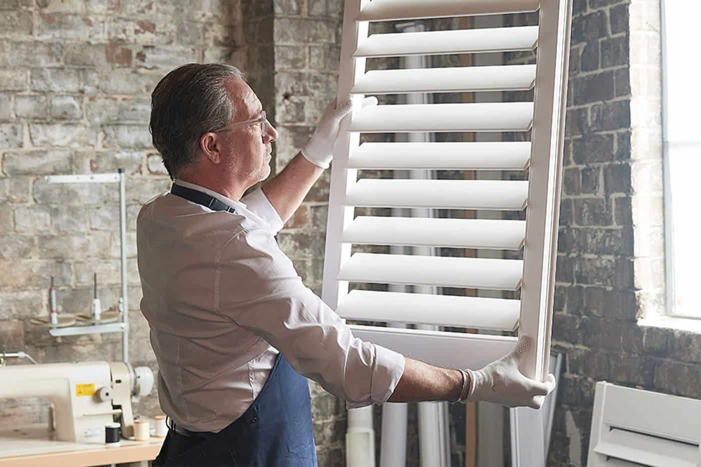 luxaflex-curtains-benefits-11 A sophisticated craftsman holding a window panel, customising to fit the window frame perfectly. Made in Australia. Available in Complete Blinds Brisbane.