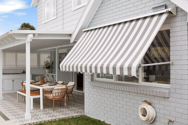 Outside view of a home patio and garden with mid-century design style, featuring System 2000 Awning covering a big window pane, providing shade and blocking out sunlight. On display in our Complete Blinds Brisbane showroom.