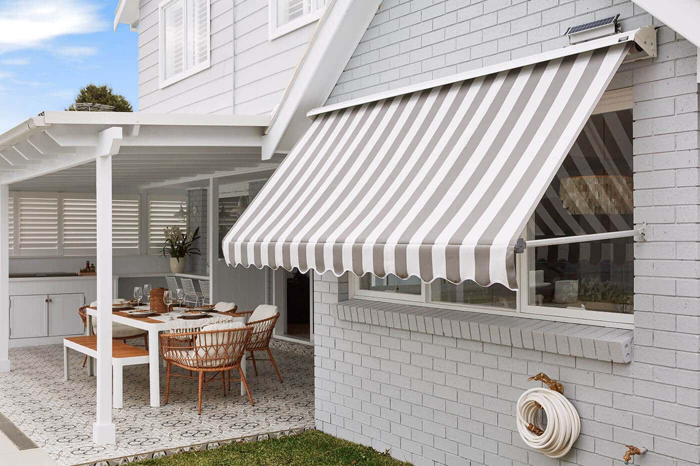 Outside view of a home patio and garden with mid-century design style, featuring System 2000 Awning covering a big window pane, providing shade and blocking out sunlight. On display in our Complete Blinds Brisbane showroom.