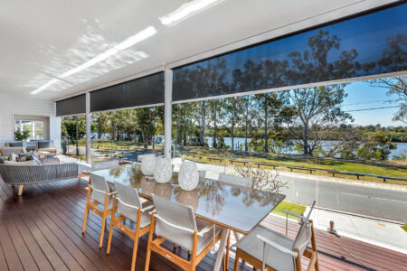 A home dining area with large window panes looking out to the garden, featuring Evo awnings for privacy and to block out sunlight. Installed by Complete Blinds Brisbane.