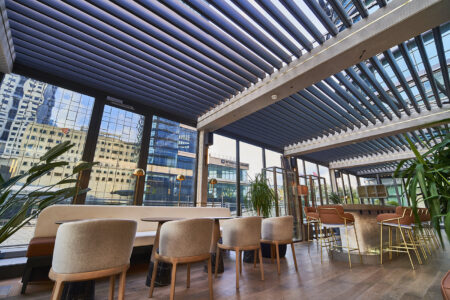 A fancy dining restaurant with sky view featuring Retractable Louvre Roof Pergola Awnings by Complete Blinds Australia.