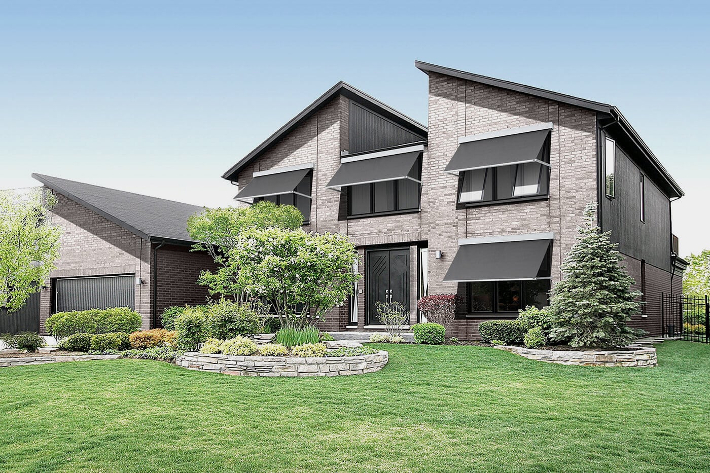 A modern and classical grey and black home design with large front lawn, featuring black Evo awnings installed at patio and home windows. By Complete Blinds Australia.