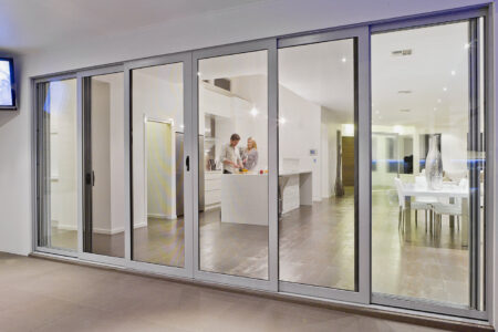 Crimsafe glass doors installed in a home, we can see a modern and aesthetic home kitchen through the glass doors. By Complete Blinds Brisbane.
