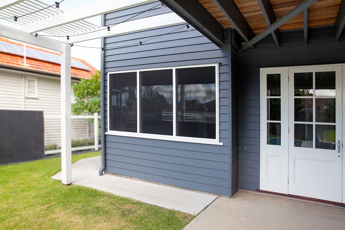 Crimsafe window screen in heritage cream powder-coat frame colour complementing a Brisbane Queenslander home exterior